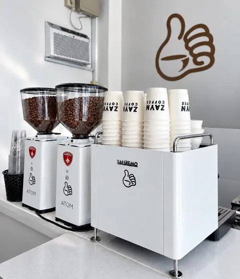 The coffee bar at Zayn Coffee with grinders, stacked Zayn cups and the espresso machine