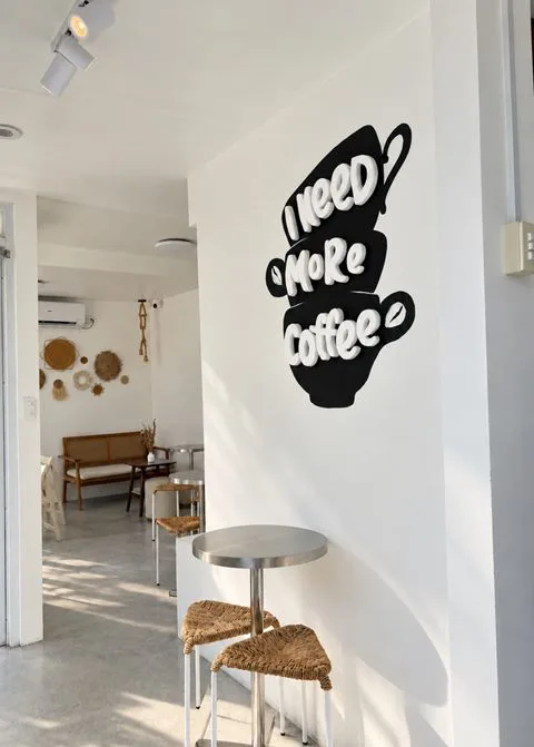 An “I need more coffee” wall graphic in the hallway at Zayn Coffee