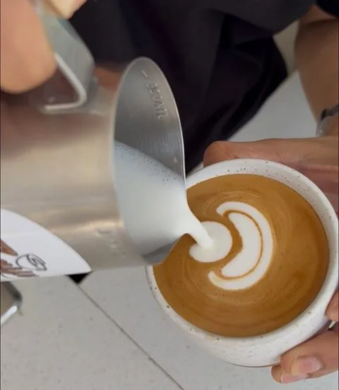 Barista pouring latte art at Zayn Coffee