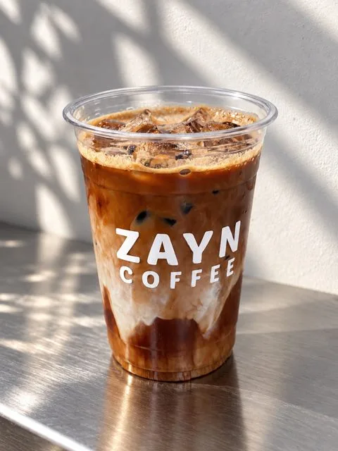 Iced Cafe Mocha in a ZAYN COFFEE cup on a steel counter in sunlight