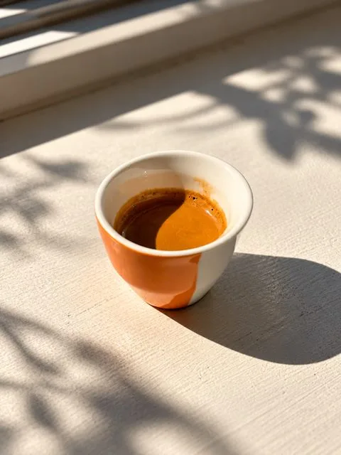 A shot of espresso in a small cup in morning sunlight at Zayn Coffee