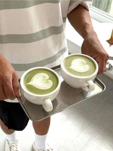 Two hot matcha lattes served on a steel tray at Zayn Coffee