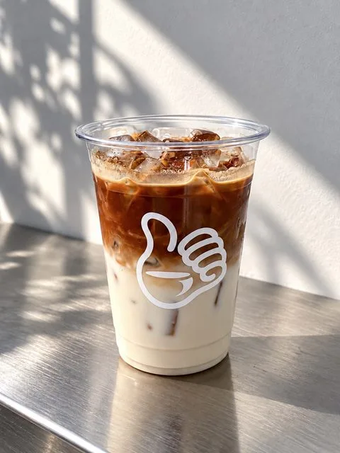 Iced Spanish Latte in a Zayn Coffee cup on a steel counter