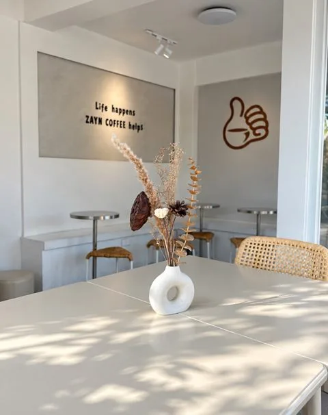 A table with a vase of dried flowers in the seating area at Zayn Coffee